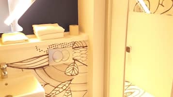 Une salle de bain comprenant des toilettes, un lavabo et un espace douche.