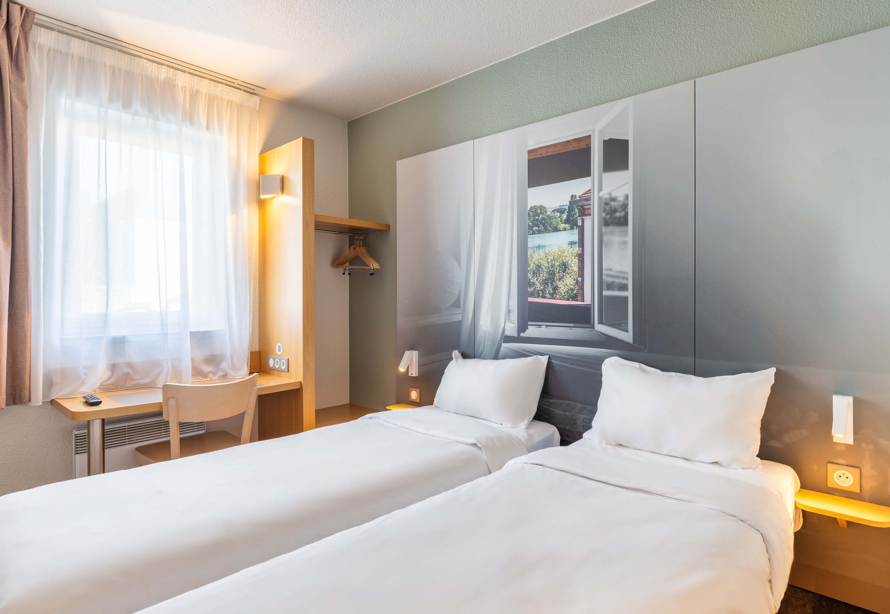 Une chambre d’hôtel avec deux lits, un bureau et une fenêtre donnant sur un paysage agréable.