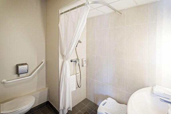 A bathroom with a shower, toilet, and handrails. - B&B Hôtel Lyon Saint-bonnet Mi-plaine (Saint-Bonnet-de-Mure)