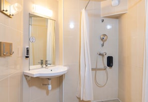 Een moderne badkamer met een wastafel, spiegel en douche.