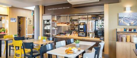 A café with tables and chairs, a coffee machine, and a refrigerator.