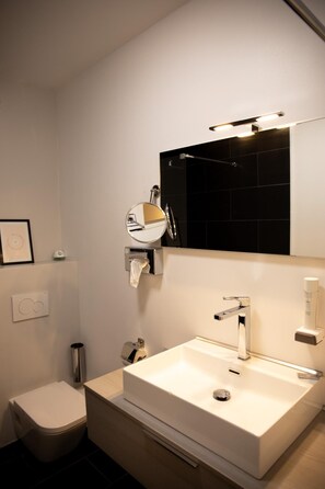A modern bathroom with a white sink, a mirror, and a toilet. - Minotel Le Bourgogne (Evian-les-Bains)
