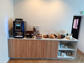 A breakfast bar with a coffee machine, jars of spreads, and baskets of pastries. - Inter-hotel D'angleterre (Fecamp)