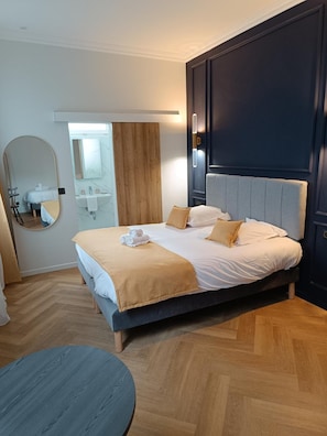 Een hotelkamer met een groot bed, een ronde tafel, een spiegel en een wand van hout.