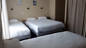 Una habitación de hotel con dos camas individuales, una mesita de noche y una pequeña mesa.