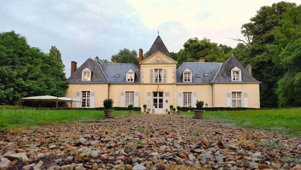 Une grande maison à deux étages, dotée d’une façade symétrique, de nombreuses cheminées et d’une entrée centrale.