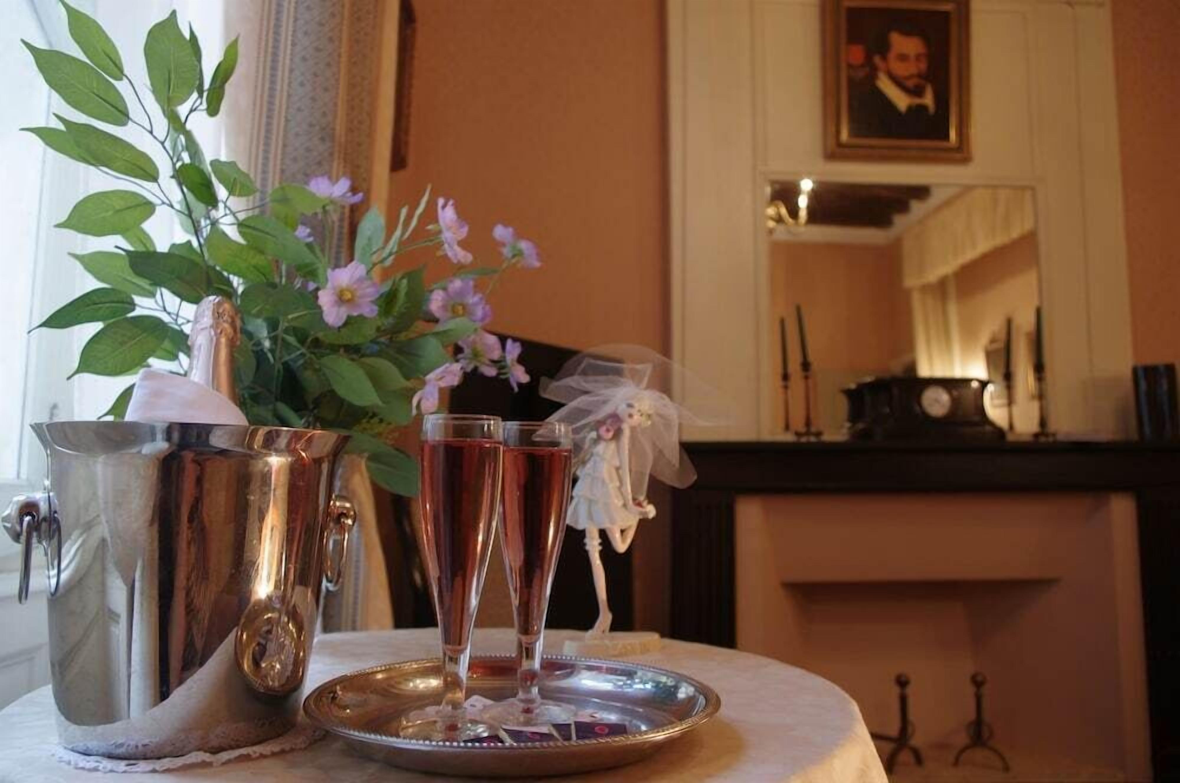 A table with a silver pitcher, two champagne flutes, and a tray with a floral arrangement.