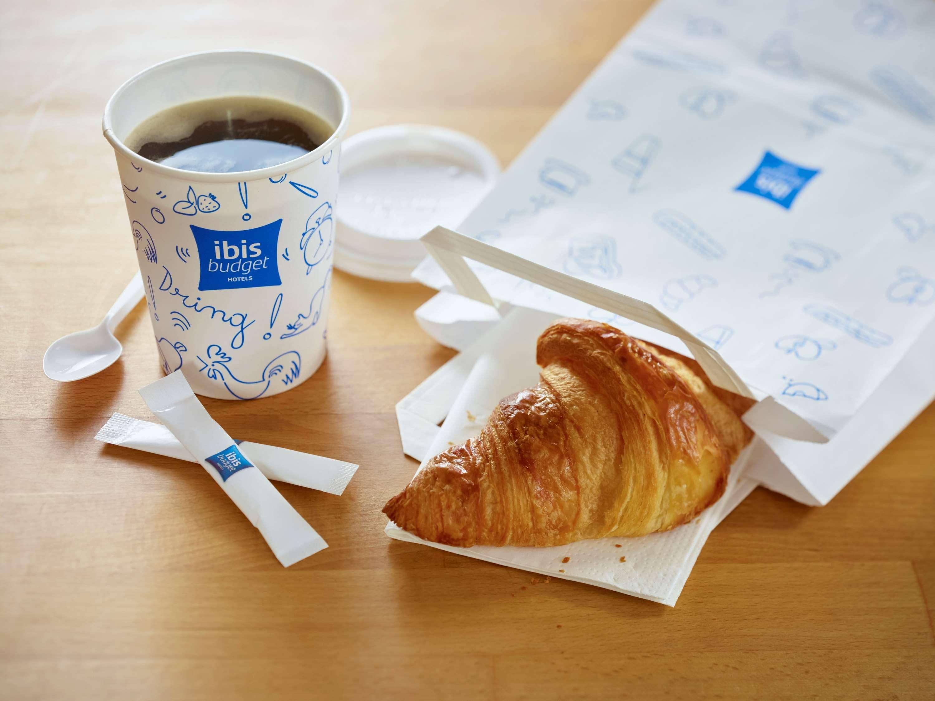 Un croissant, une tasse de café et un menu aux couleurs de l’hôtel.