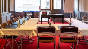 A conference room with a high ceiling, exposed beams, and a large screen for presentations. Tables and chairs are arranged for meetings. - Grand Hotel Benodet Abbatiale (Benodet)