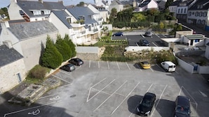 An aerial view of a parking lot with multiple cars, a designated disabled parking space, and surrounding residential buildings. - Grand Hotel Benodet Abbatiale (Benodet)