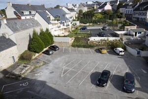 Vue aérienne d’un parking contenant de nombreuses voitures, une place de stationnement réservée aux personnes handicapées et des immeubles résidentiels environnants.
