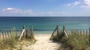 A sandy beach path leading to the ocean, surrounded by wooden posts and grass. - Grand Hotel Benodet Abbatiale (Benodet)