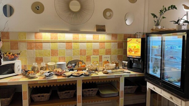 A breakfast bar with a coffee machine, a refrigerator displaying food, and a tiled backsplash. - Hotel De France (Bordeaux)