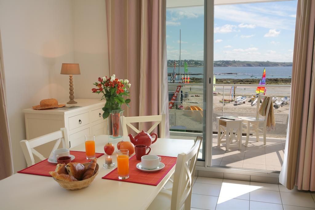 Un coin repas avec une table mise pour le petit-déjeuner, une vue sur la plage et un balcon donnant sur la mer.