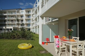 Et hotel med et overdækket udendørs siddeområde, en swimmingpool og en have.