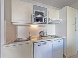 A compact kitchen with a microwave, coffee maker, and dishwasher.