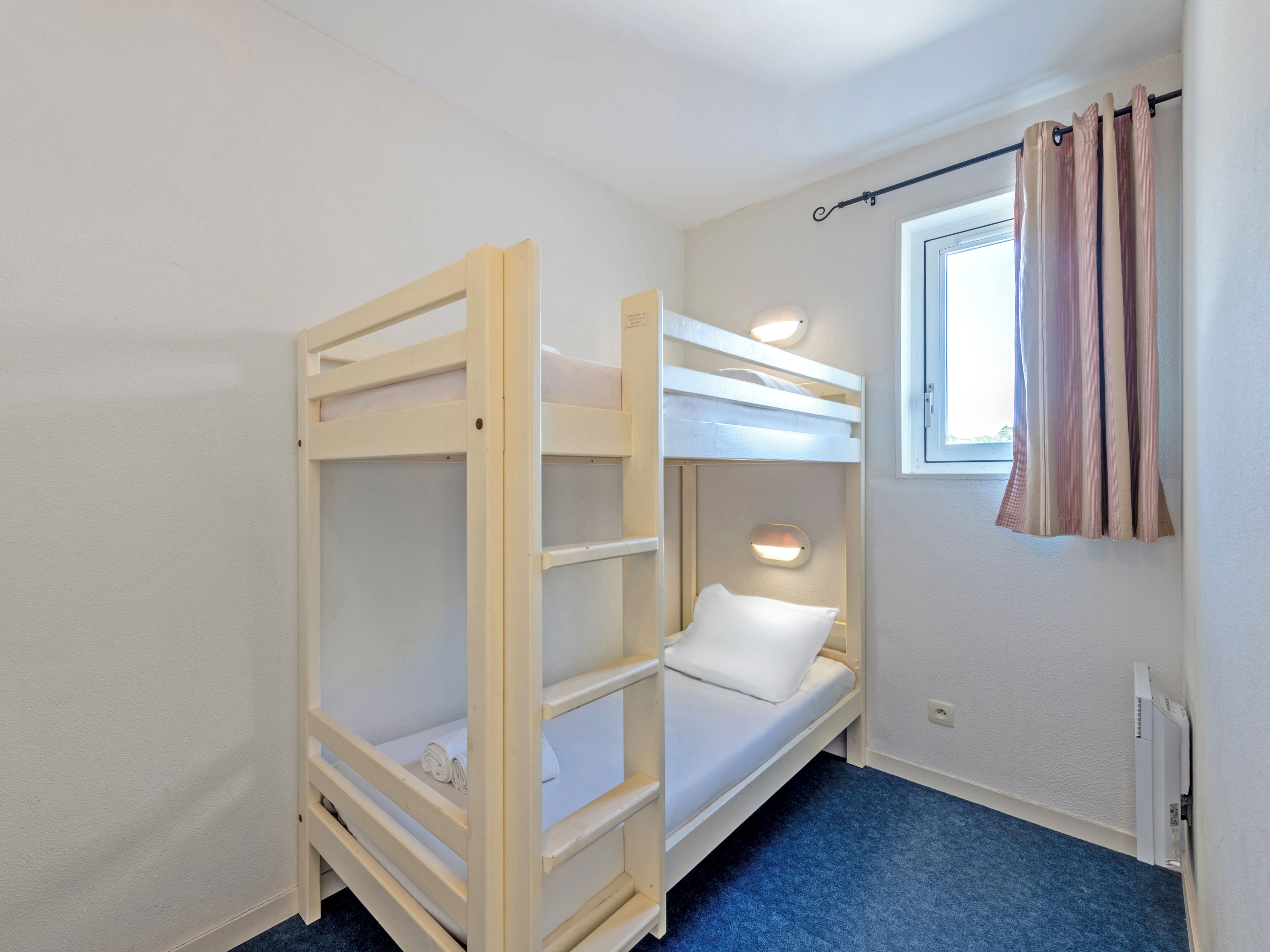 A bunk bed room with a window and a curtain.