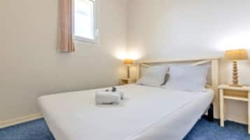 A hotel room with a single bed, a bedside table with a lamp, and a window with curtains.