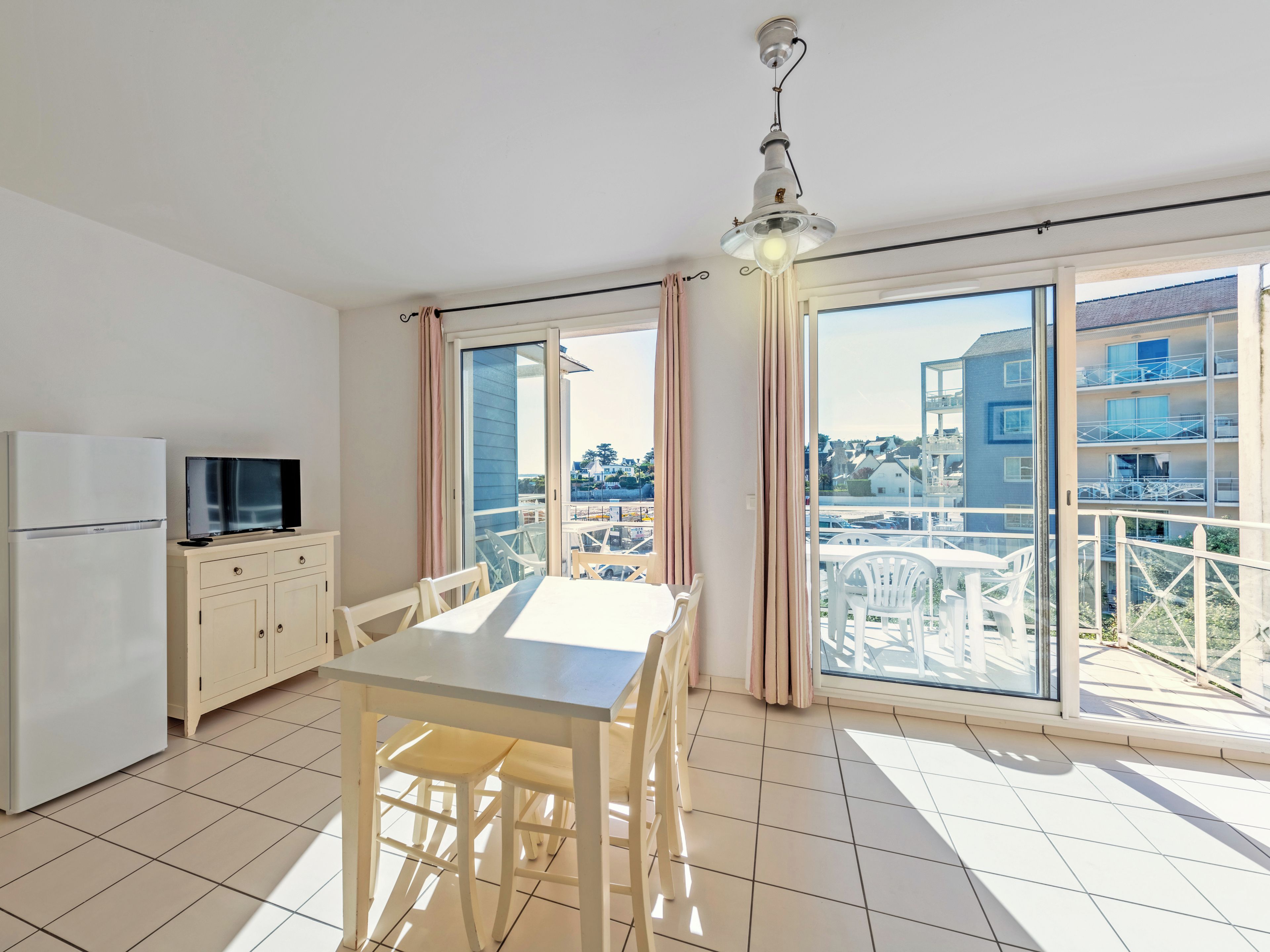 Un apartamento moderno con cocina, comedor y grandes puertas correderas de vidrio que dan a un balcón.