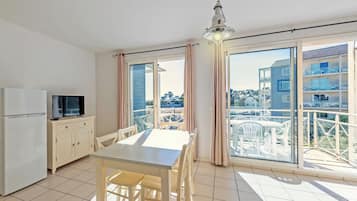 Un apartamento moderno con cocina, comedor y grandes puertas correderas de vidrio que dan a un balcón.