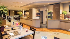 A modern restaurant with a central island, dining tables, and chairs. - Brit Hotel Tours Sud Le Cheops (Joue-les-Tours)