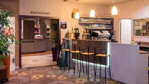 A restaurant with a bar area, bar stools, and a counter with a coffee machine. - Brit Hotel Tours Sud Le Cheops (Joue-les-Tours)
