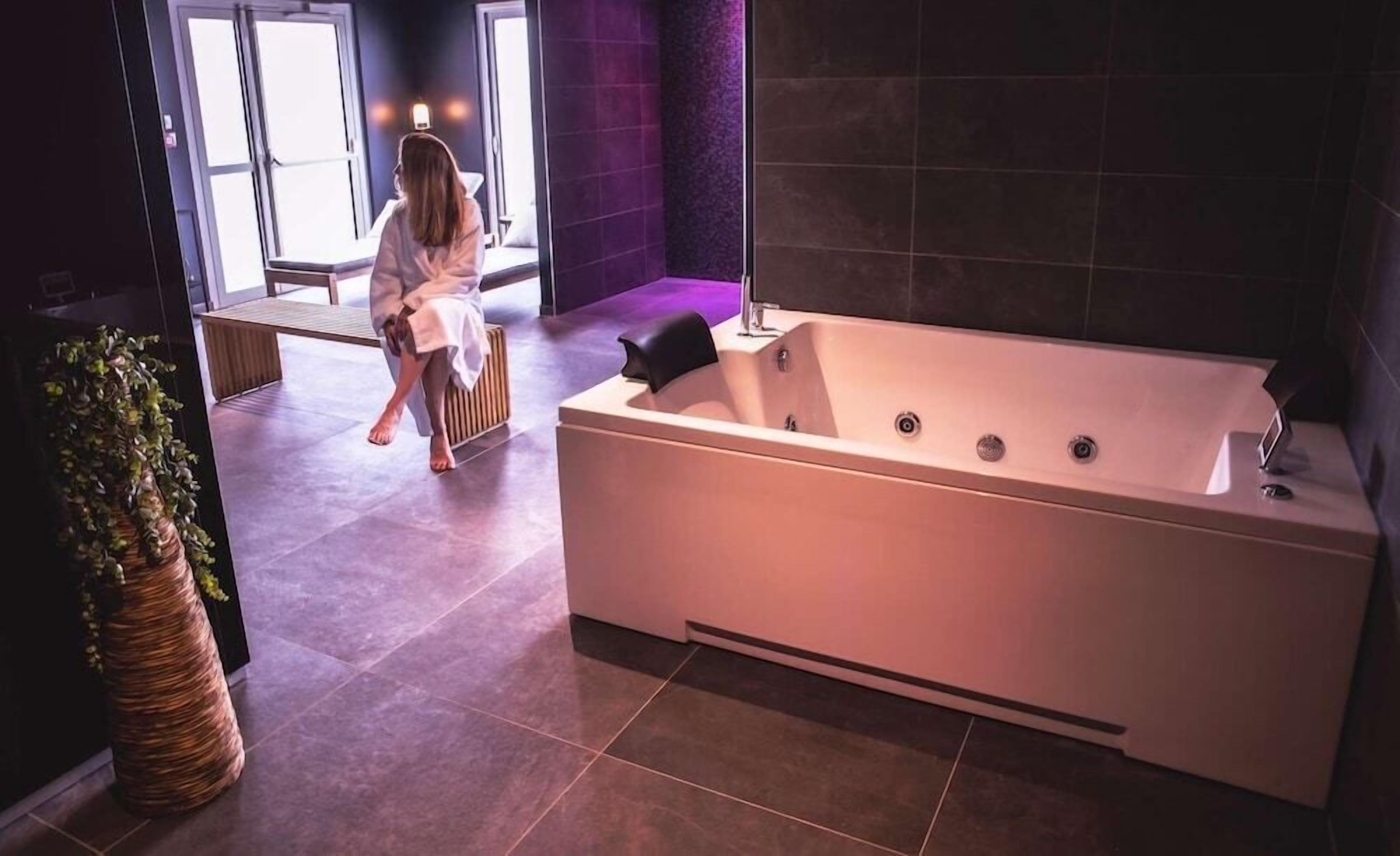 Une salle de bain moderne avec une grande baignoire, une plante en pot et un banc.