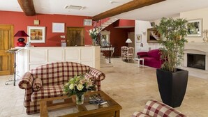 A spacious living room with a checkered sofa, a coffee table, and a large potted plant. - Relais Du Silence Le Clos De Pradines (Saint-Quentin-la-Poterie)