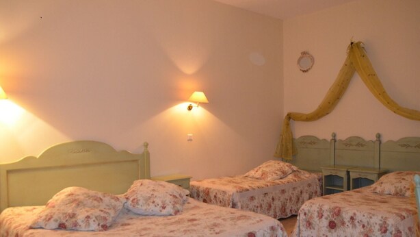A room with two single beds, a nightstand, a lamp, and a decorative curtain. - Relais Du Silence Le Clos De Pradines (Saint-Quentin-la-Poterie)
