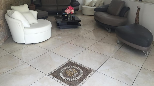 Un soggiorno con parete in pietra a contrasto, un divano, un tavolino da caffè con fiori e un tappeto decorato.