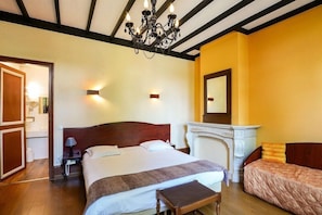 A hotel room with a large bed, a fireplace, a mirror, and a wooden bench. - Hotel Notre Dame (Valenciennes)