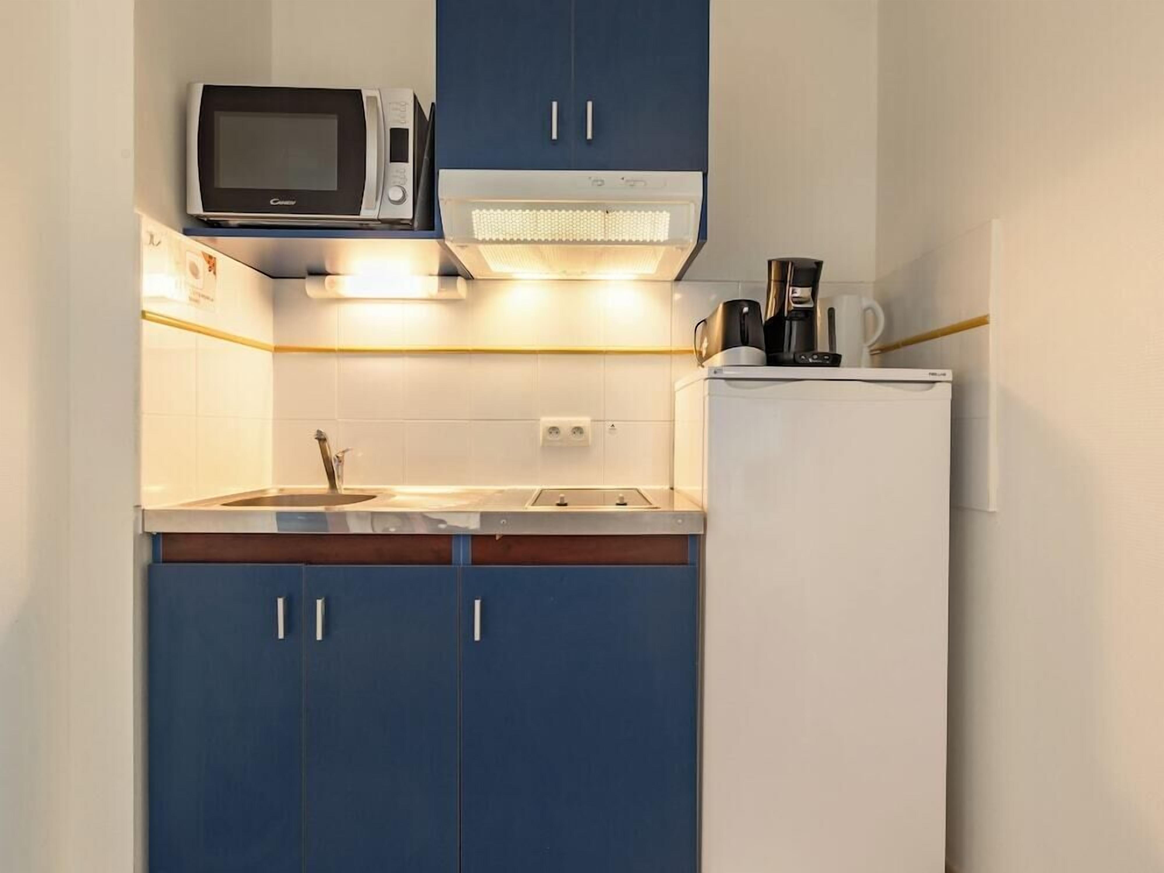 A compact kitchen with a microwave, a coffee maker, and a refrigerator.