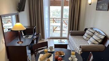 Una habitación acogedora con una mesa de comedor lista para el desayuno, una computadora portátil y un sofá con un cojín escocés.