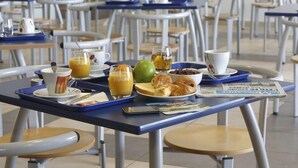 A breakfast setup with a tray containing orange juice, a green apple, croissants, and a bowl of cereal. - Residence Appart Vacances Pyrenees 2000 (Bolquere)