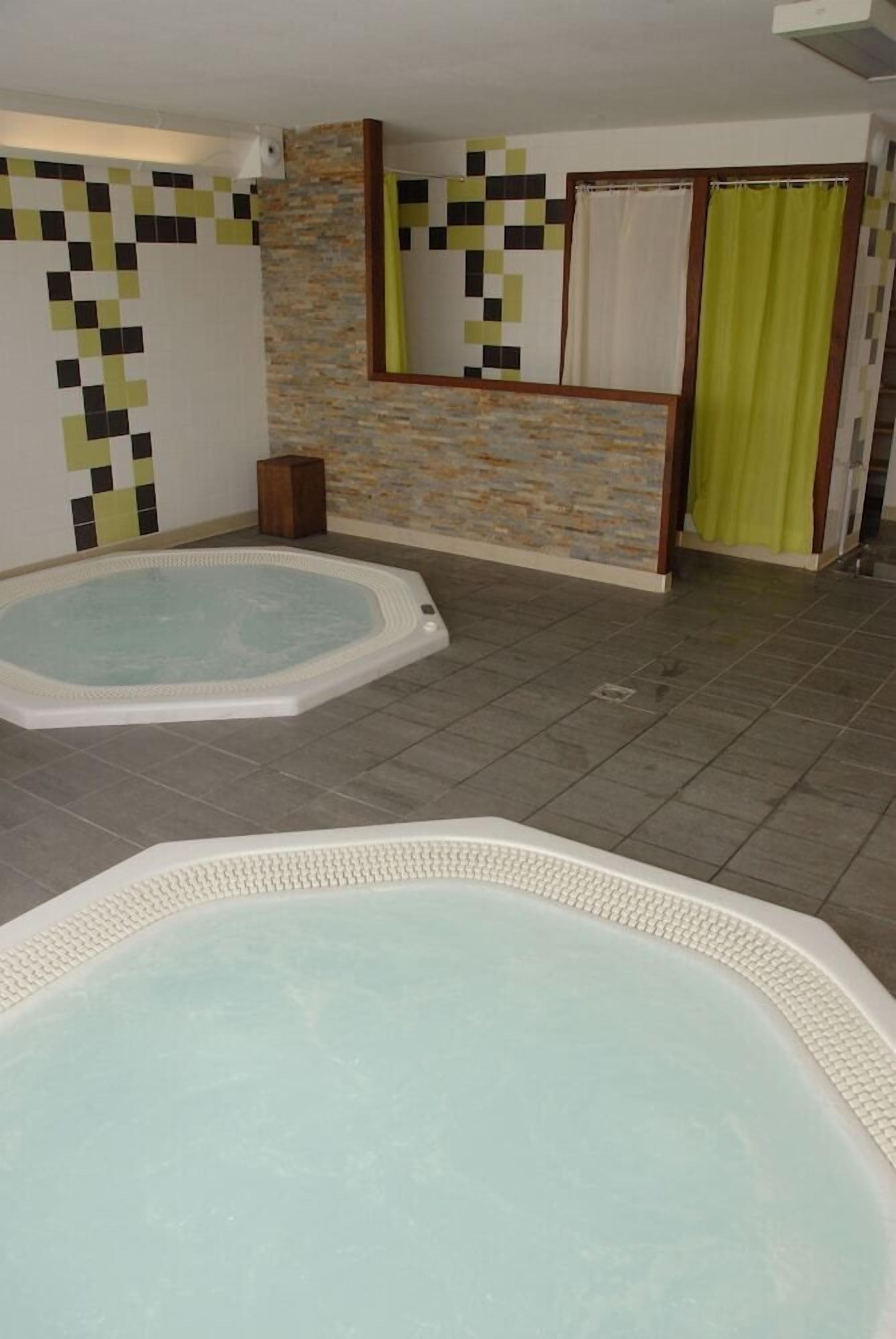 Uma área de spa com duas banheiras de hidromassagem, uma parede de pedra e um banco de madeira.