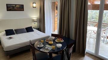 Ett hotellrum med en säng, ett matbord med frukost och utsikt över omgivningarna.