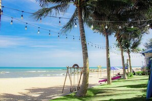 Ein Strand mit Palmen, einer Schaukel und Lichterketten.