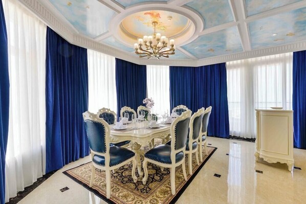 Un comedor formal con una mesa redonda, sillas tapizadas en azul y una araña.