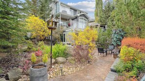A two-story house with a stone pathway leading to a patio area with outdoor furniture. - 2 Suites, 6 Beds +Sofa Bed | Sauna|Sleeps 14 (Calgary)