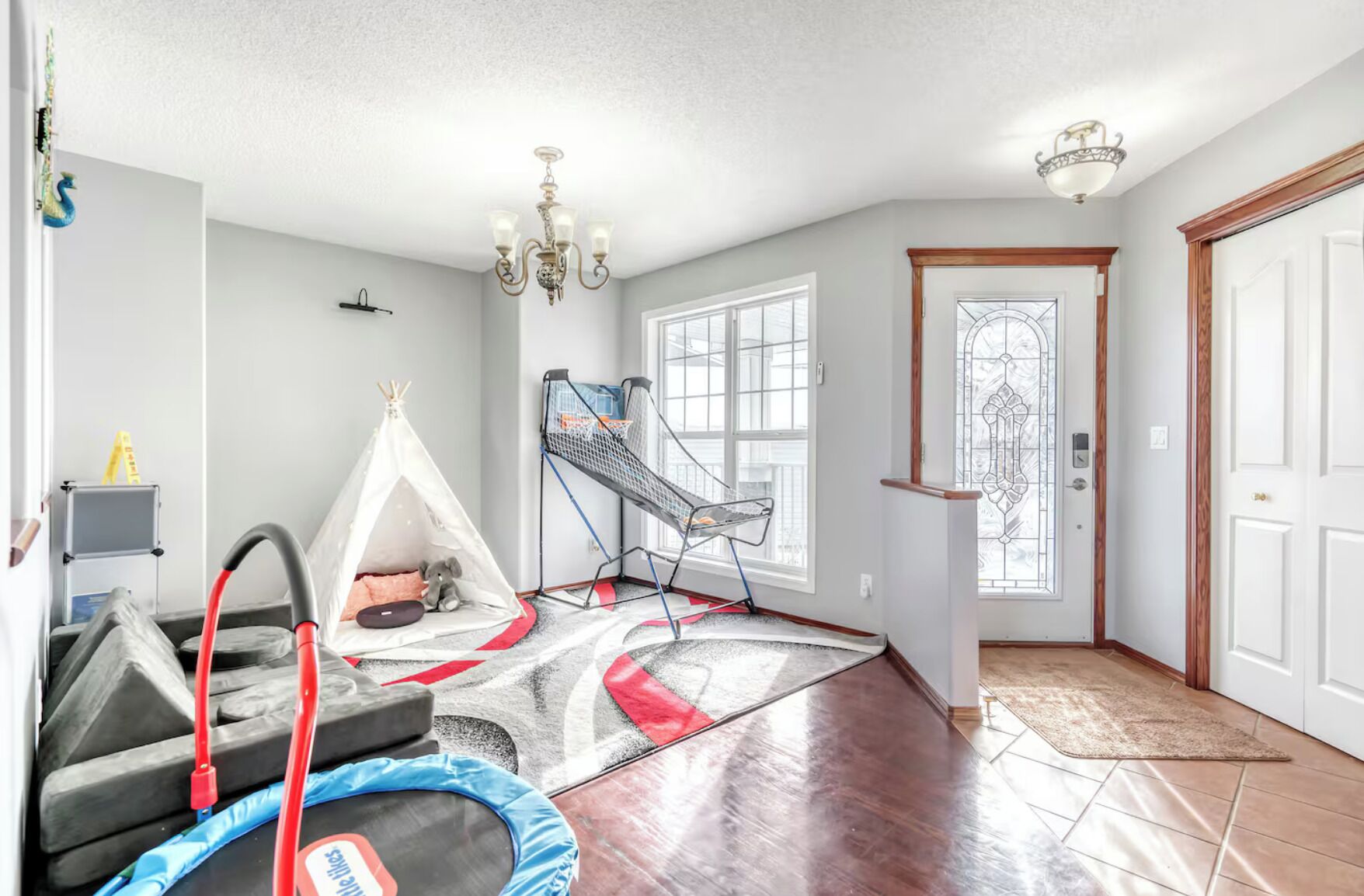 A spacious room with a large window, a sliding door, and a chandelier.