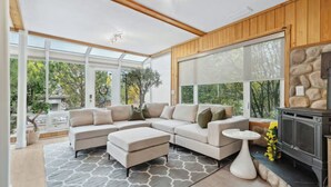 A modern living room with a sectional sofa, a fireplace, and large windows offering a view of the outdoors. - 2 Suites, 6 Beds +Sofa Bed | Sauna|Sleeps 14 (Calgary)