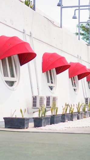 A building with multiple arched windows and red awnings. - Kapal Garden Hotel (Malang)