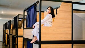 A modern hotel room with a wooden bunk bed and a curtain.