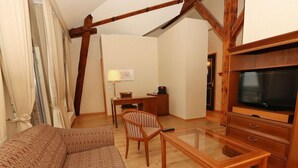 Ein gemütliches Wohnzimmer mit Sofa, Couchtisch, TV-Schrank und Schreibtisch mit Lampe.