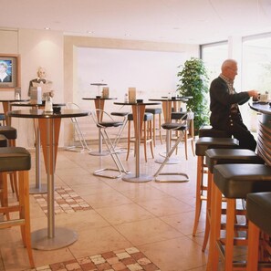A restaurant with round tables and chairs, a potted plant, and a statue on the wall. - Seligweiler (Elchingen)