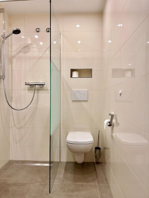A modern bathroom with a glass-enclosed shower, a toilet, and a sink. - Seligweiler (Elchingen)