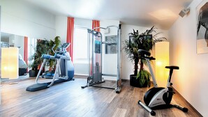 Un gimnasio en casa con equipo de ejercicio, un espejo grande y plantas en macetas.
