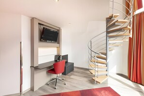 A modern room with a desk, chair, and a spiral staircase. - Select Hotel A1 Bremen (Stuhr)
