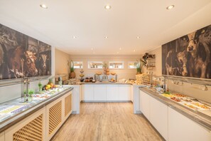 A buffet with various food items and a central island with a vase of flowers. - Select Hotel A1 Bremen (Stuhr)