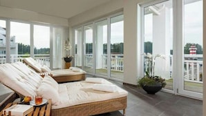 A spacious balcony with a wicker sofa and a potted orchid. - Precise Resort Hafendorf Rheinsberg (Rheinsberg)
